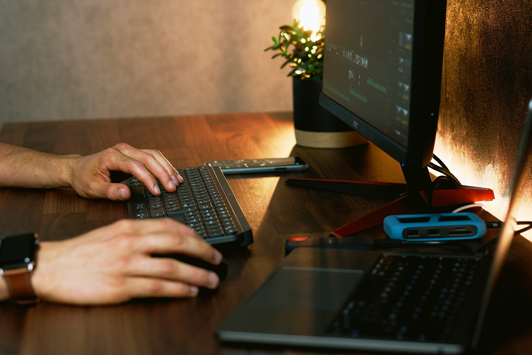 A person typing on a keyboard in front of a monitor displaying a user interface