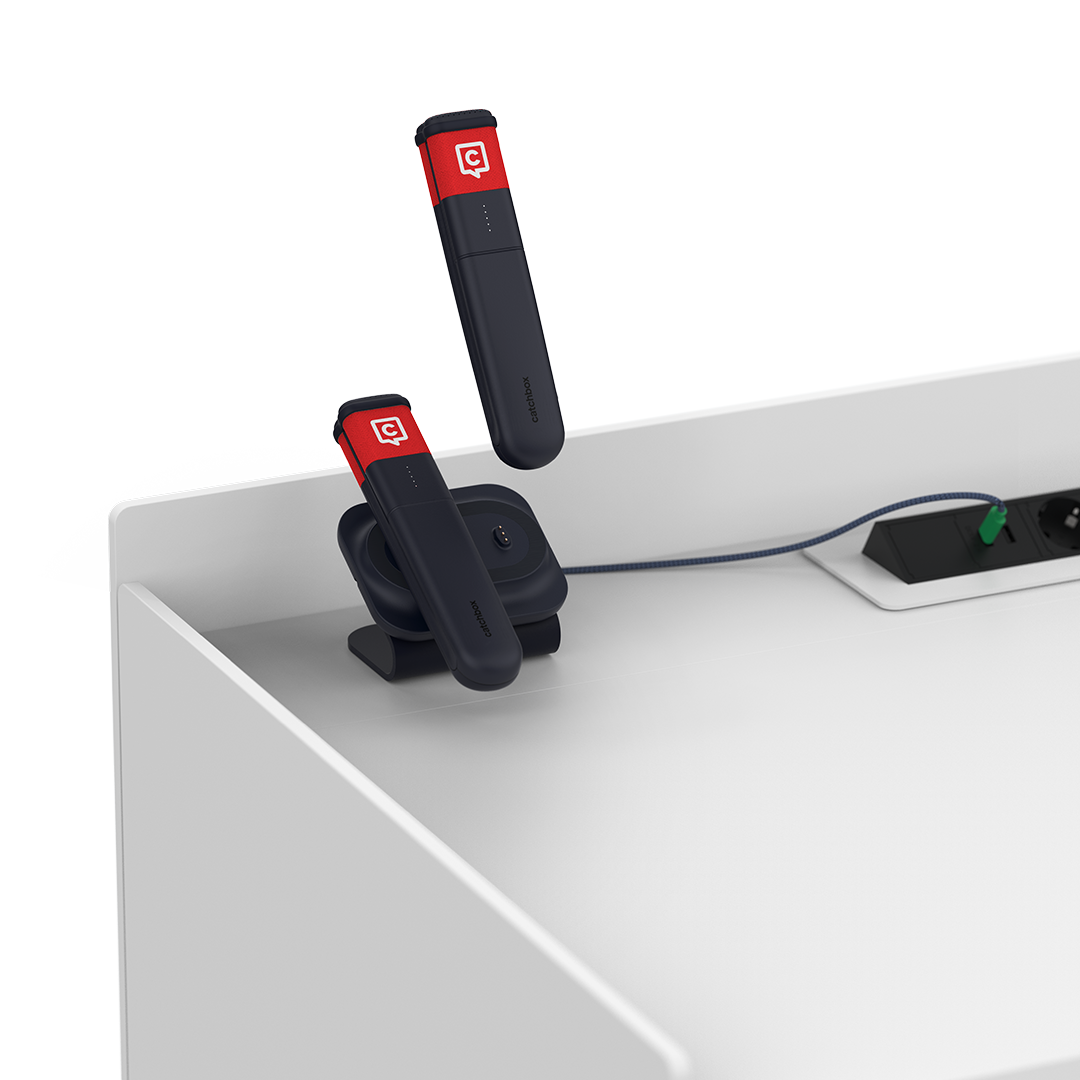 Two Catchbox handheld microphones resting on a Dual Charging Dock, placed on a lectern.
